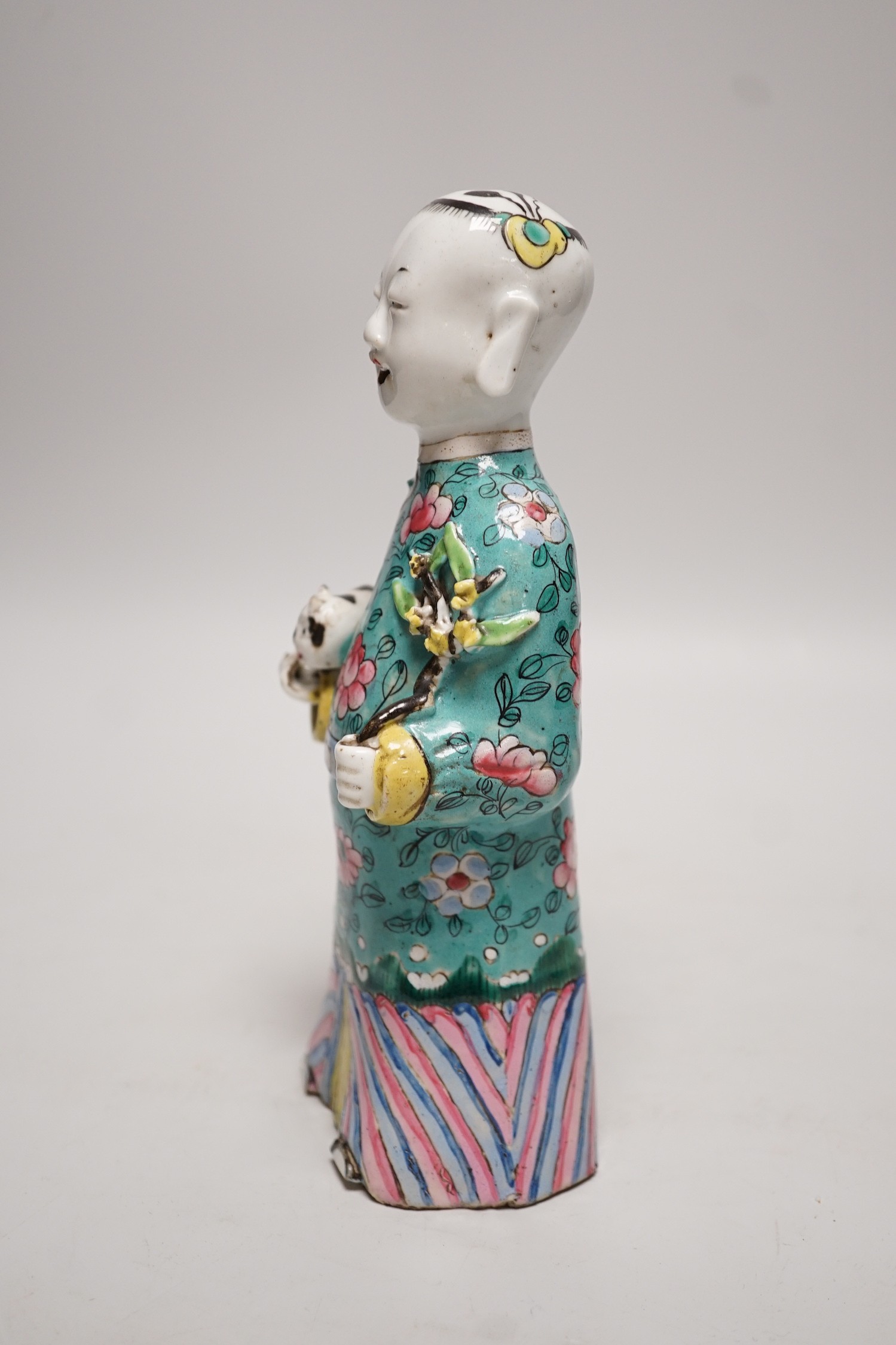 An early 19th century Chinese enamelled porcelain figure of a boy holding a cat and a sprig of prunus, 20cm